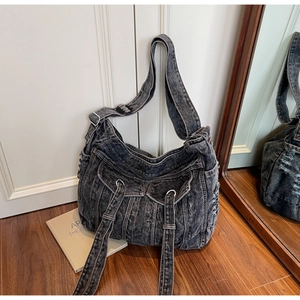Detail of black washed denim bag featuring cargo pockets and silver metal ring accents