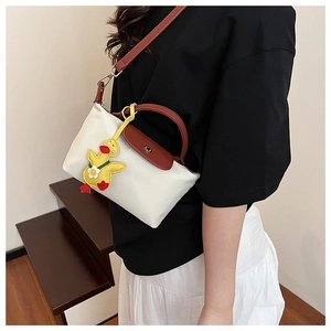 Detailed shot of cream mini tote bag with brown leather handles and yellow duck charm