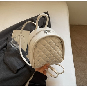 Close-up of cream quilted mini backpack with rhinestone embellishments and zip closure