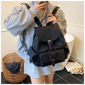 Detail view of a black pebble leather backpack with drawstring flap and silver buckles