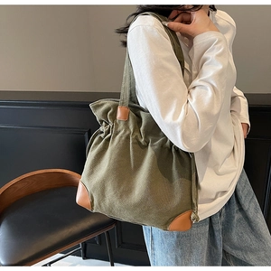 Close-up of vintage dark green canvas bucket bag with brown leather reinforcement details