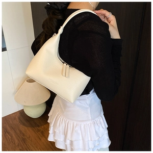 Dettaglio della borsa hobo minimalista in pelle crema con grana litchi e tirazip