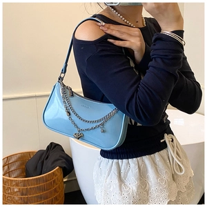 Detail of light blue hobo bag with glossy finish and silver chain with heart pendant