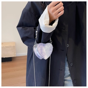 Detail of purple marble heart-shaped mini bag with chain strap worn on black coat