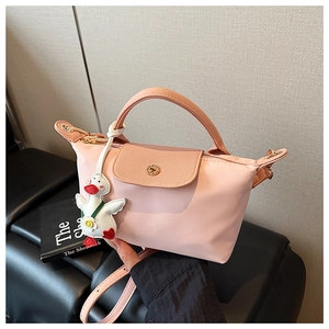 Detail view of pink nylon handbag with leather flap and cute white duck charm accessory