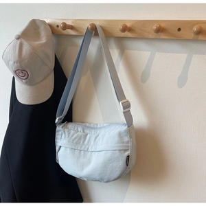 Detail of light blue nylon crescent bag with adjustable strap and BÜFAN side label
