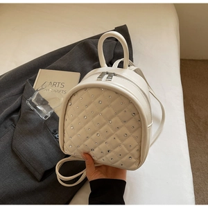 Close-up of quilted cream mini backpack with diamond stitching and rhinestone accents