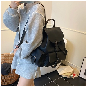 Detail of black pebbled leather backpack with drawstring closure and buckle pockets