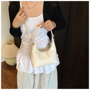 Borsa hobo bianco crema con trama litchi mostrata a mano e a tracolla sulla modella