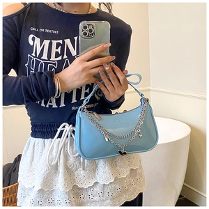 Detail of light blue patent leather hobo bag with silver chains and heart charms