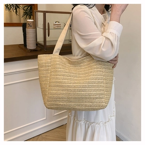 Close-up of a minimalist cream woven straw tote bag featuring detailed horizontal texture