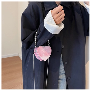Pink heart-shaped mini purse with silver beaded handle and chain strap on hand