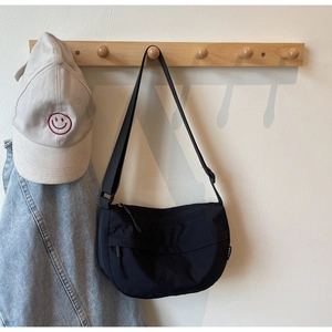 Detail view of black nylon crescent bag with adjustable strap on wooden wall hook