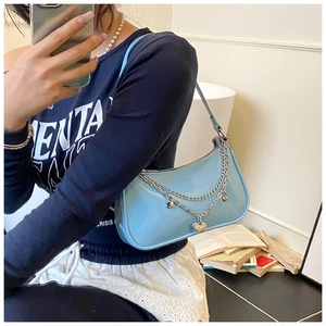 Detail of sky blue patent leather half-moon bag with silver heart chain accessory
