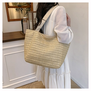 Detail of woven straw tote bag with fabric straps shown on a model in a cafe setting