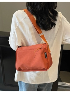 Orange canvas crossbody messenger bag with adjustable strap and multiple compartments