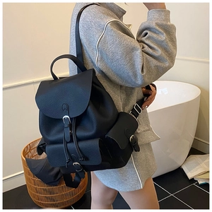Detail of black pebbled leather backpack with flap buckles and drawstring closure