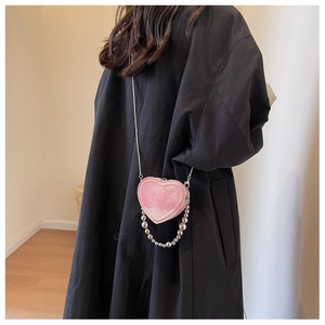 Detail view of pink heart-shaped mini bag with pearly bead handle and metal chain strap