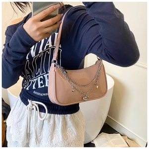 Detail of nude pink patent leather bag with silver heart chain and metallic charms