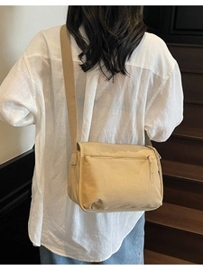 Minimalist beige canvas crossbody bag with adjustable wide strap shown on a model