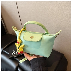 Detail of mint green nylon handbag featuring leather handles and a yellow duck charm