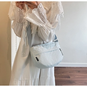 Adjustable light blue nylon crescent crossbody bag shown in a casual lifestyle setting