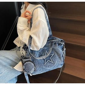 Detail of blue denim tote bag with star stitching, featuring a round coin purse charm
