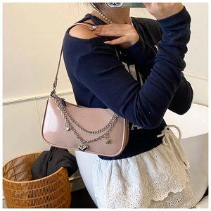 Detail of pink patent leather baguette bag with silver chain and heart pendant