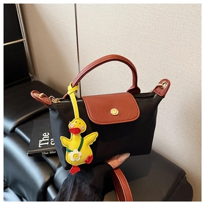 Close-up of contrast nylon crossbody bag with brown leather handles and duck pendant