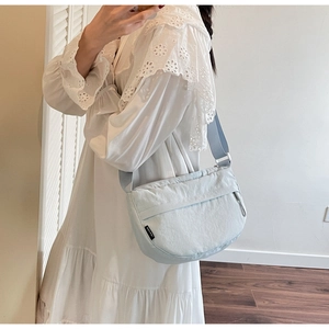Detail of light blue nylon crescent bag with adjustable strap shown in mirror selfie