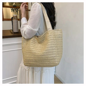 Detailed texture of woven straw tote bag with wide fabric shoulder strap for summer use