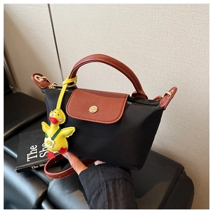 Detail of black nylon handbag with red leather handle and yellow duck charm accessory