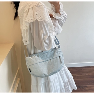 Detail of light blue nylon crescent bag showing soft texture and adjustable strap