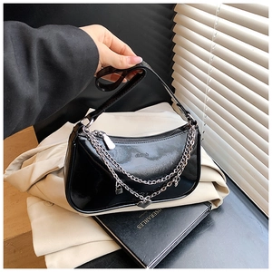 Detail of black glossy shoulder bag with silver chains and heart lock charms in use