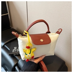 Detail of white nylon crossbody bag with red leather trim and a cute yellow duck charm