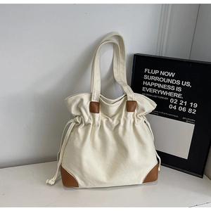 Detail of canvas tote bag with brown leather trim and unique drawstring closure design