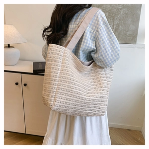 Detail showing the large capacity and woven texture of the off-white straw tote bag