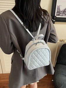 Light blue quilted mini backpack with rhinestone details shown on model in indoor setting