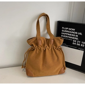 Detail of caramel canvas tote bag with drawstring closure and reinforced faux leather base