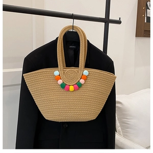 Détail du sac cabas en paille fait main avec pompons colorés et texture tressée