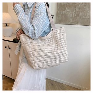Detail of the woven texture and fabric handle on a large beige straw tote bag