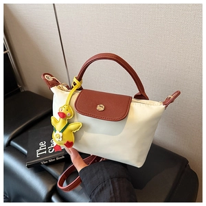 Detail of mini cream nylon handbag with brown leather flap and cute duck pendant