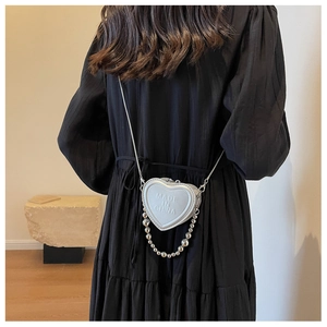 Mini heart-shaped crossbody bag featuring textured logo and elegant bead chain