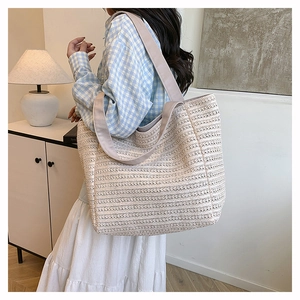 Side view of large woven tote bag with beige stripes and grey wide strap on shoulder