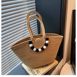 Détail du sac cabas en paille kaki avec pompons noirs et blancs et doubles anses