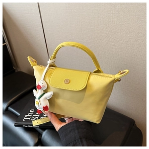 Detail of yellow nylon handbag featuring leather flap and cute white duck charm accessory