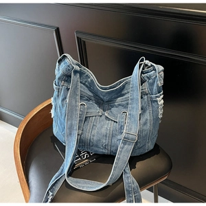 Close-up of retro denim tote bag with frayed edges, multiple pockets, and silver buckles