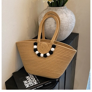 Détail de la texture d'un sac cabas tissé kaki avec pompons noirs et blancs décoratifs
