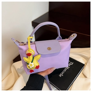 Detail of lavender square handbag with gold hardware and a cute yellow duck charm