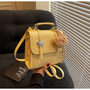 Detail of bright yellow PU leather backpack with silver star buckle and bear charm